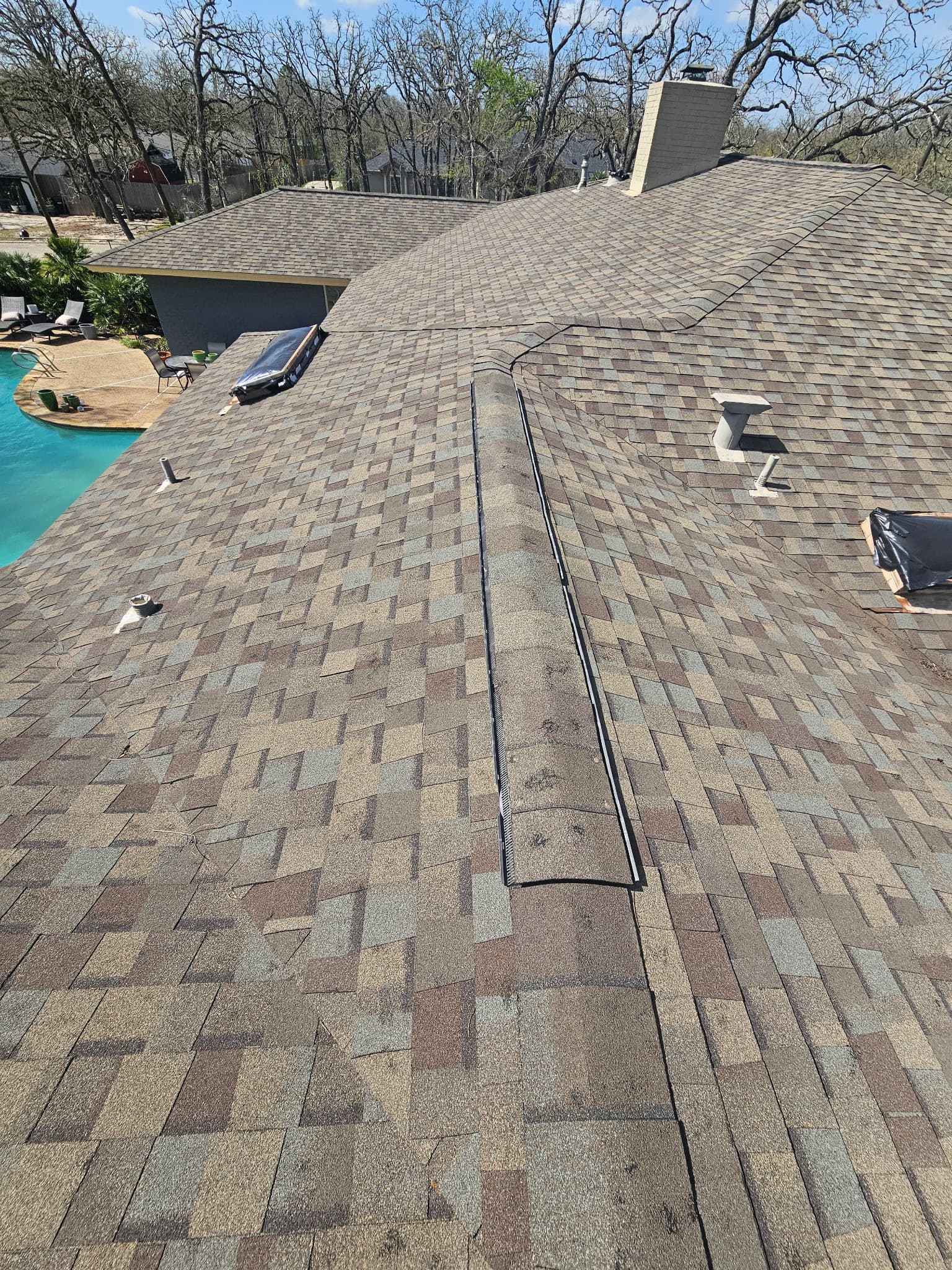 Tan and brown architectural shingles on a roof overlooking a Katy, Texas backyard pool